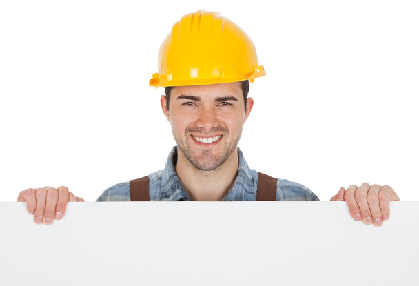 Worker wearing hard hat and holding empty banner - Foto, imagen
