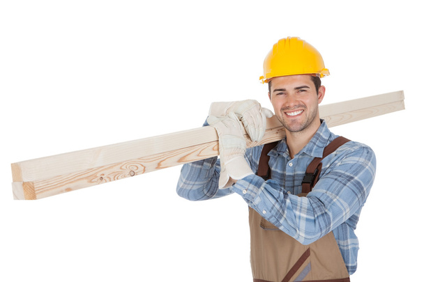 Worker wearing hard hat and carrying timber - Photo, Image
