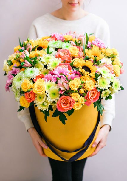 Bouquets de luxe de fleurs mélangées dans la boîte à chapeau. roses dans les mains femmes
. - Photo, image