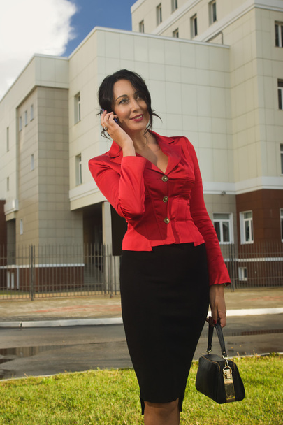 Ελκυστική γυναίκα σε κόκκινο κοστούμι σε ένα δρόμο - Φωτογραφία, εικόνα
