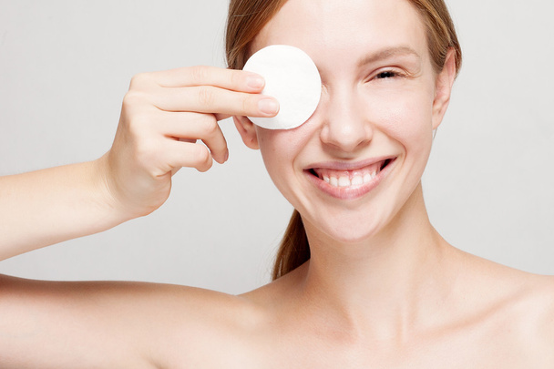 happy woman cleaning her face with cotton pads - Foto, Imagen