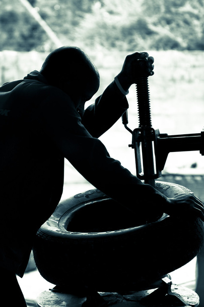 Mechanic at work fixing tyres in a garage in Namibia. Duo toned - Photo, Image