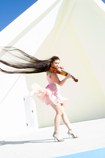 Скрипаль грає на сцені під відкритим небом в рожевій сукні
 - Фото, зображення