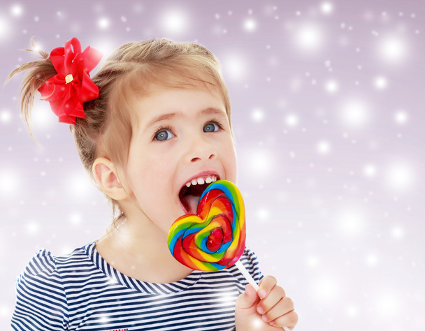 Girl licks candy on a stick - 写真・画像