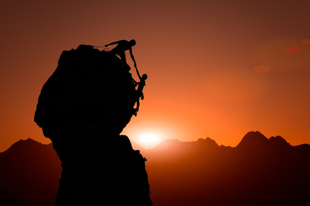Команда альпіністів допомагає підкорити вершину під час заходу сонця
 - Фото, зображення
