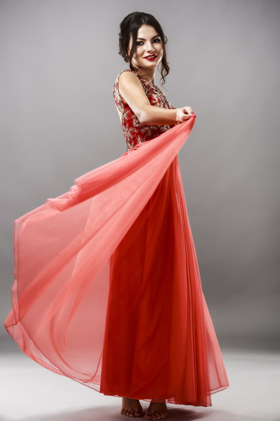 πορτρέτο μιας όμορφης νεαρής γυναίκας με κόκκινο φόρεμα. - Φωτογραφία, εικόνα