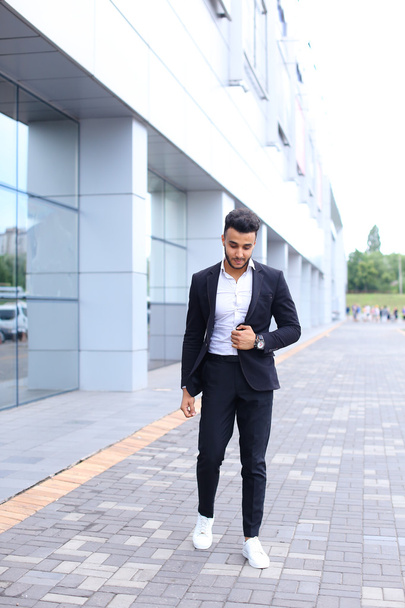 Arabic guy in business center stands smiling walking slow - Foto, imagen