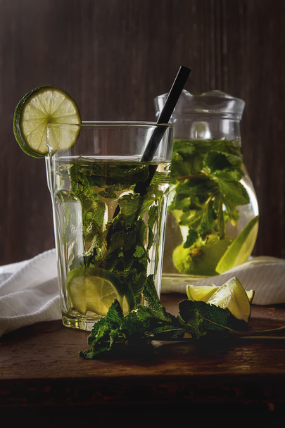 Mint iced tea with lime in the glass. Dark background. - 写真・画像