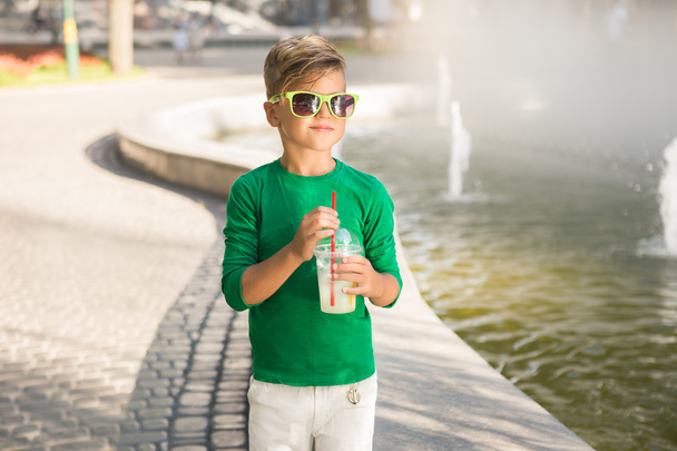 Stylish little Boy holding a cocktail in his hand . He's wearing glasses - Photo, Image