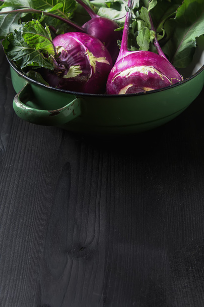 Ripe purple turnips with green leaves. Dark background. Autumn p - Foto, afbeelding
