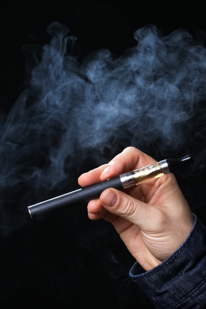 Hand met elektronische sigaret op een zwarte achtergrond - Foto, afbeelding