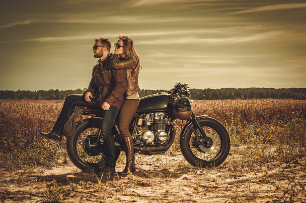 スタイリッシュなカフェ レーサーのカップルにおいてビンテージ カスタム バイク. - 写真・画像