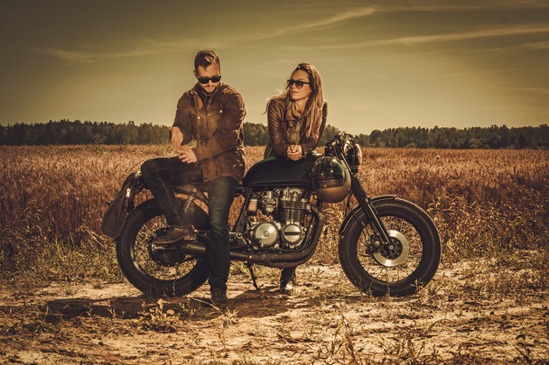 Stylish cafe racer couple on the vintage custom motorcycles in a field. - Photo, Image