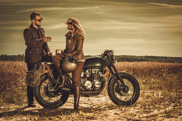 stilvolles Café-Racer-Paar auf den alten Custom-Motorrädern auf einem Feld. - Foto, Bild