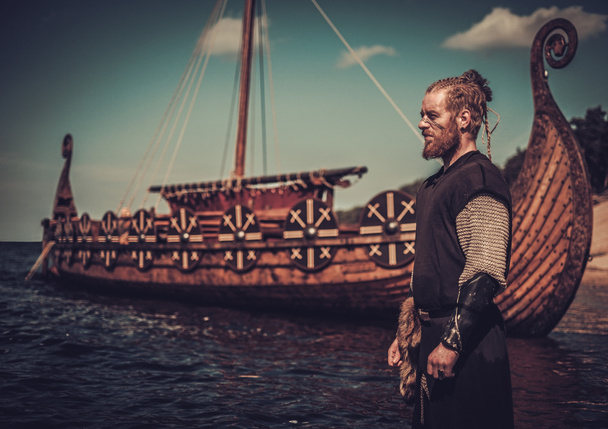 Viking bojovník s mečem stojící poblíž Drakkar na břehu moře. - Fotografie, Obrázek
