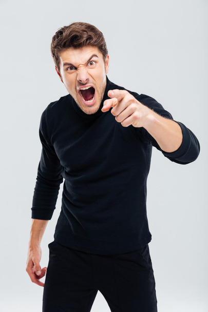 Mad furious young man pointing on you and shouting - 写真・画像