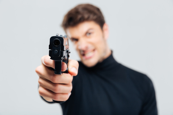 Closeup of angry young man pointing with gun on you - Photo, Image