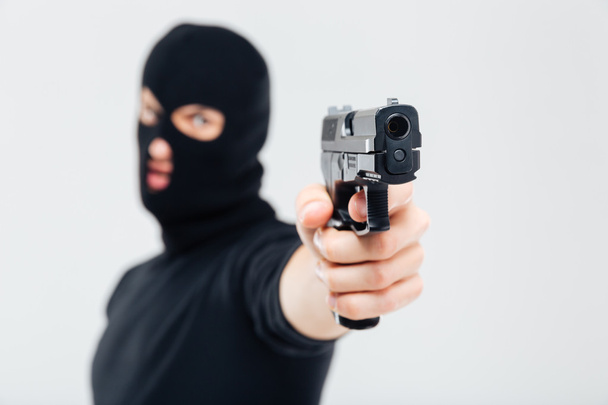 Man robber in balaclava pointing with gun - Foto, afbeelding