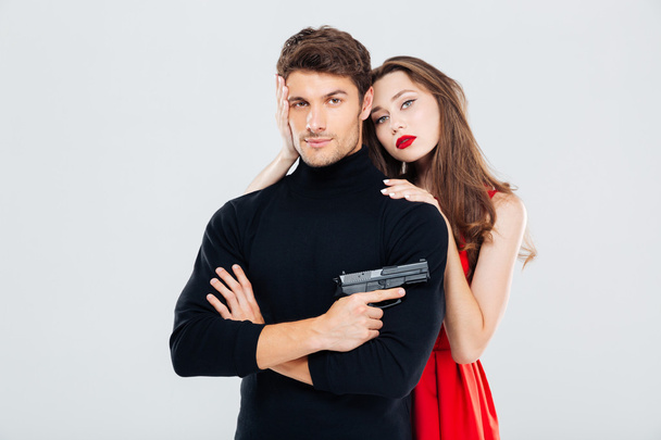 Beautiful young couple hugging and posing with gun - Fotó, kép