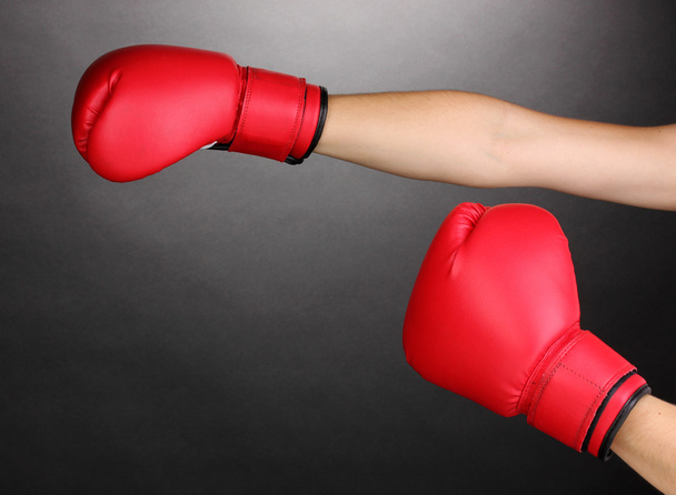 Red boxing gloves on hands on grey background - Photo, image