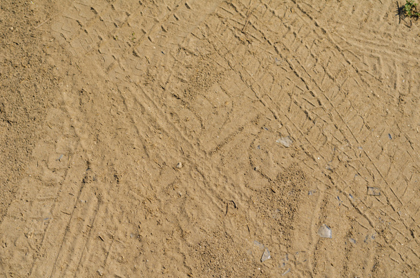 Texture of yellow sand with marks of car tyres and foot prints - Фото, изображение