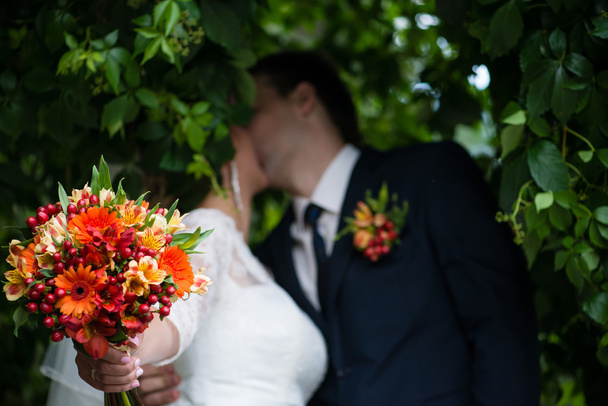 結婚式の花束と新婚夫婦のキス、浅いと背景をぼかし - 写真・画像