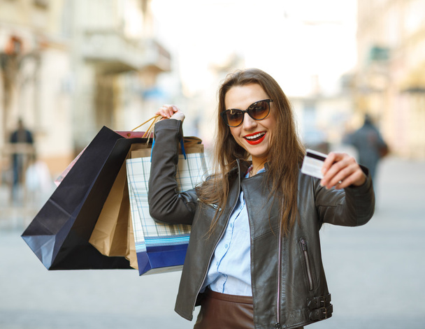 Mulher bonita com sacos de compras e cartão de crédito nas mãos
  - Foto, Imagem