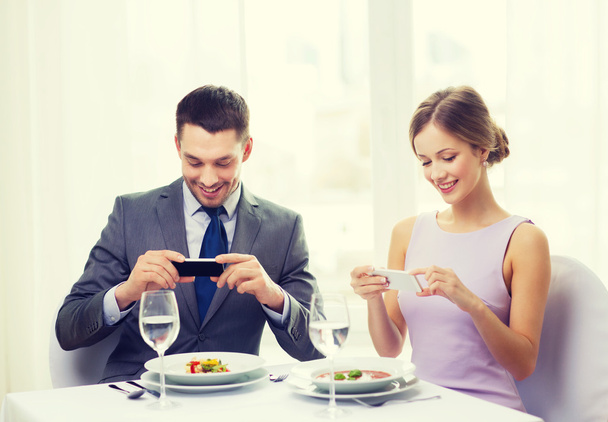 smiling couple with appetizers and smartphones - Fotó, kép