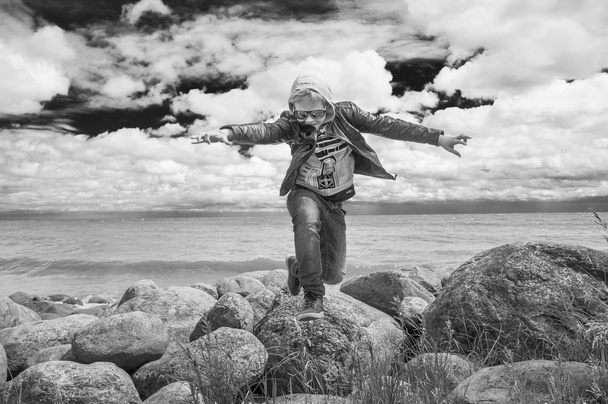 niño está saltando de las rocas
  - Foto, imagen