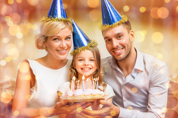 smiling family in blue hats with cake - Фото, изображение