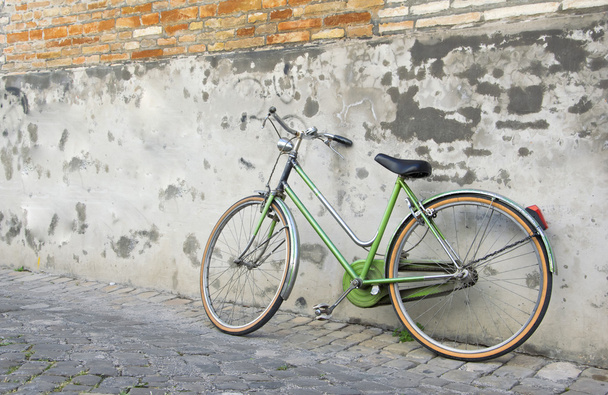 Oude retro groene fiets leunend tegen een muur - Foto, afbeelding