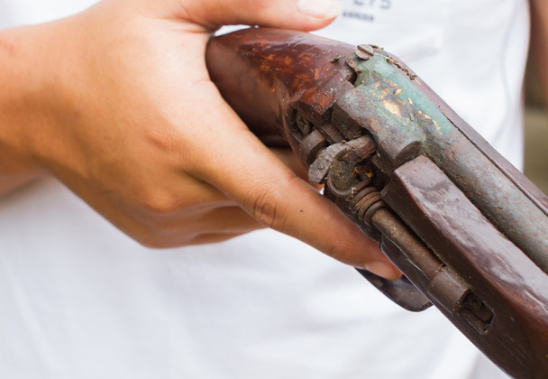 foto horizontal de mão closeup segurando arma velha, foco seletivo na arma
. - Foto, Imagem
