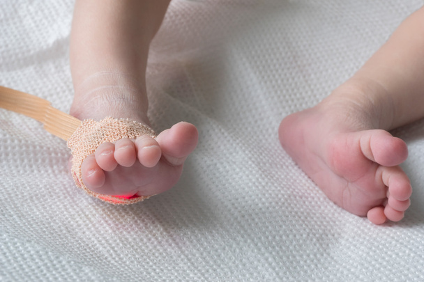 Czujnik pulsoksymetru puls na nogi noworodka w zbliżeniu łóżko szpitalne - Zdjęcie, obraz