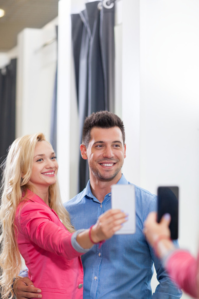 Young Couple Taking Selfie Photo Fitting Room Fashion Shop, Happy Smiling Man And Woman Shopping Customers Trying Clothes - Zdjęcie, obraz