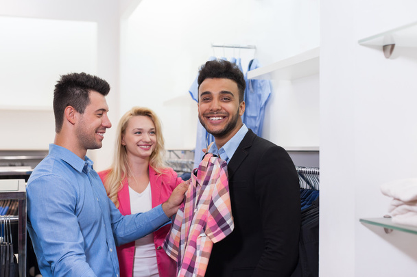 Junge Leute kaufen ein, glücklich lächelnde Freunde Kunden im Modegeschäft passendes Hemd - Foto, Bild