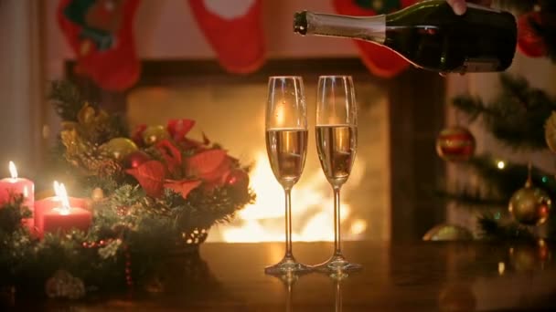 Zbliżenie dłoni strugach szampana w okularach na stole przy kominku - Materiał filmowy, wideo