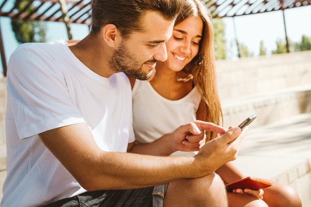 Portrait of beautiful young couple using mobile phone. - Foto, Imagen