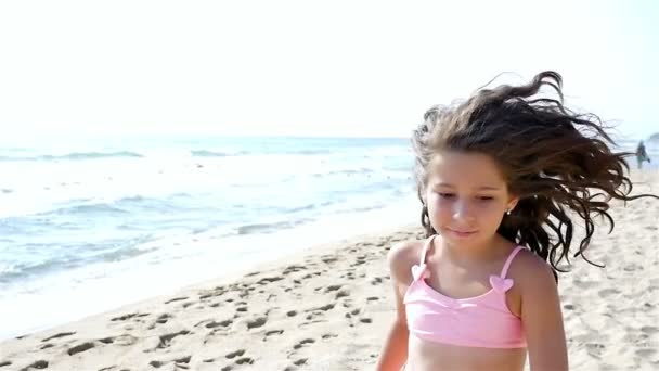Slow motion of a cute little girl in swimsuit running and playing at the sea beach - Footage, Video