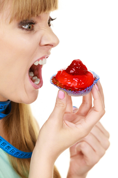 Женщина держит кекс, пытаясь противостоять искушению
 - Фото, изображение