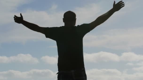  man backlit raises his arms to the sky - Footage, Video