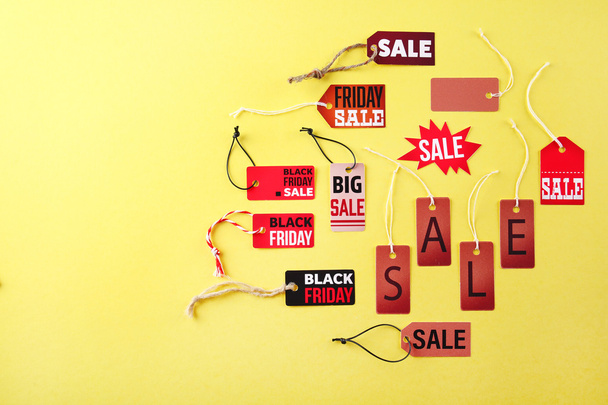 Paper tags met strijkers en woord verkoop op gele achtergrond - Foto, afbeelding