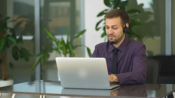 Hombre de negocios sonriente con auriculares interactuando en su oficina
 - Imágenes, Vídeo