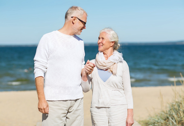 happy senior couple holding hands on summer beach - Photo, Image