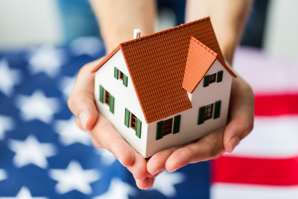 close up of hands holding house over american flag - 写真・画像