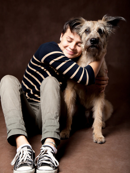 Beautiful young woman with a funny shaggy dog on a dark backgrou - Фото, изображение