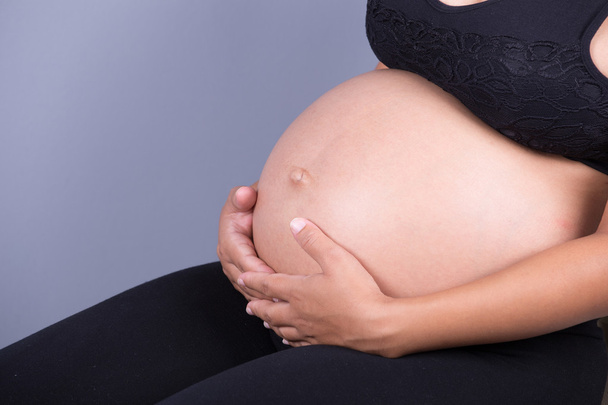 Close-up of pregnant woman belly with her hand - Fotoğraf, Görsel