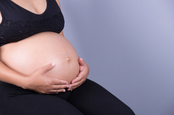 Close-up of pregnant woman belly with her hand - Foto, imagen