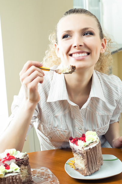 Cheerful blond young woman eating torte - 写真・画像