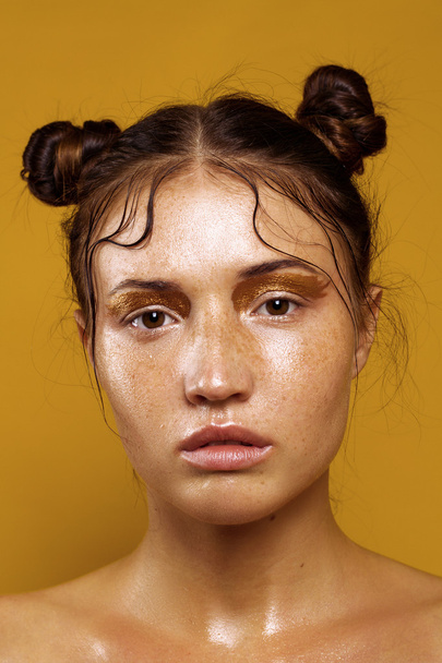 Portrait of a beautiful girl on a yellow background with the effect of wet skin - Photo, Image