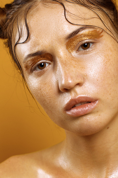 Portret van een mooi meisje op een gele achtergrond met het effect van natte huid - Foto, afbeelding